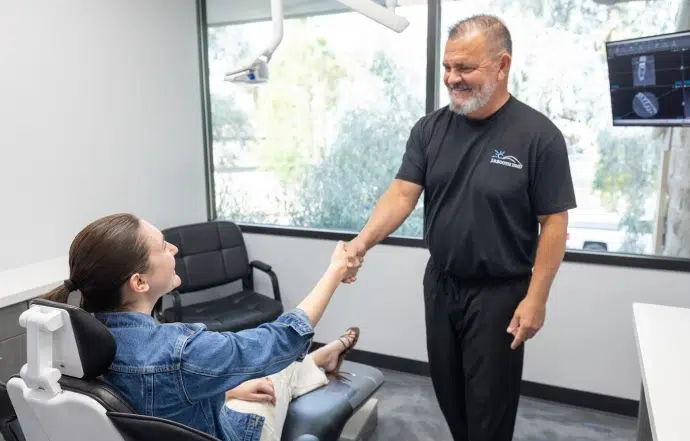 A clinician consulting gently with a seated patient about a dental treatment